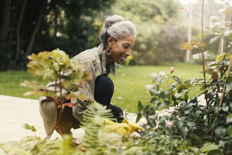a smiling woman gardening in a lush yard